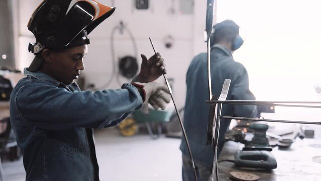 Young black male working testing steel structure in workshop with glove slow motion track right
