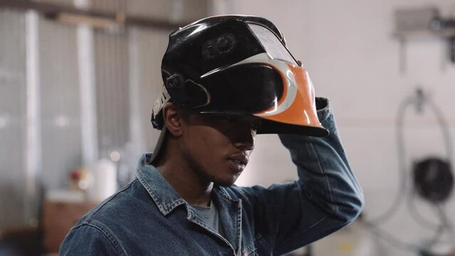 Slow motion close up young black male putting on welding helmet mask