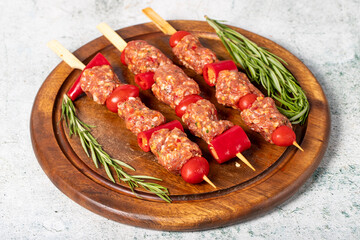 Kebab with vegetables and minced meat. Shish kebab with raw minced meat, pepper and tomato on gray background. Turkish cuisine delicacies. Local name ozel hatay kebabi