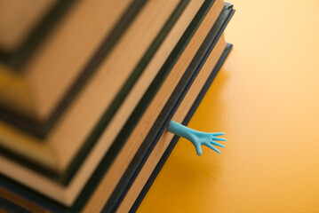 Tired student hand try to escape from many stack textbook. Concept of abstract too study hard, load...