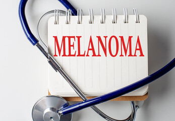 MELANOMA word on notebook with medical equipment on background