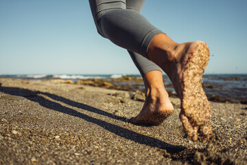 close-up of female feet barefoot running on the sand against the backdrop of the sea