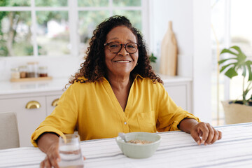 Health breakfast for a retired senior: Mature woman having cereal and water at home