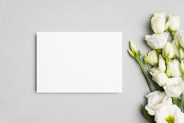 Obraz na płótnie Canvas Wedding invitation card mockup with eustoma flowers, white card with copy space