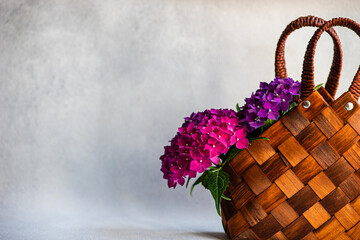 Pink and purple hydrangea flowers in a basket on a table