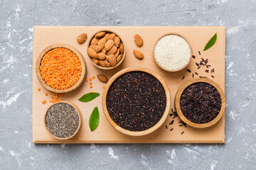 Various superfoods in smal bowl on colored background. Superfood as rice, chia, quinoa, lentils, nuts, sesame seeds, almonds. top view