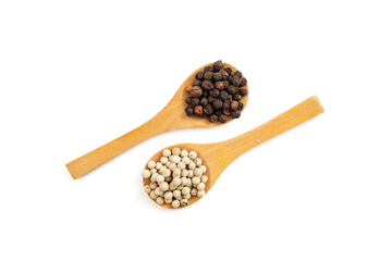 Black vs white pepper seeds in two wooden spoons, isolated on white background