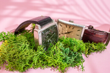 Two Generic wrist watches on green lichen sprinkled with water, resistance concept,