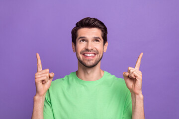 Photo of young handsome guy wear green stylish green t-shirt direct finger empty space proposition above head isolated on purple background