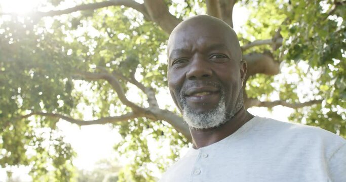 Portrait of happy african american senior man in sunny garden, slow motion