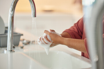 Washing hands, cleaning and person with hygiene and water for wellness in a kitchen faucet. Soap foam, sink and home with bacteria prevention and safety with disinfection with liquid before cooking