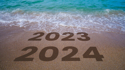 The waves erase 2023 to 2024 written in the sand by the beach. 2024.