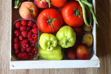 Naklejka na ściany i meble Wooden crate full of healthy seasonal fruit and vegetable. Top view, wooden background.