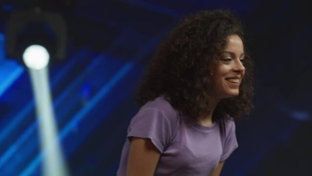 Young female woman girl dancer talent is standing on stage, talking to the judges during audition. Recording of television style broadcast talent show