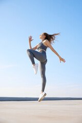 Obraz premium Young woman with slim, fit body in comfortable sportswear training outdoors on warm summer day. Stretching