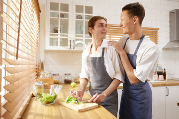 LGBT gay couple cooking vegetables together in the kitchen