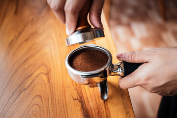 Close-up of hand Barista cafe making coffee with manual presses ground coffee using tamper on the...