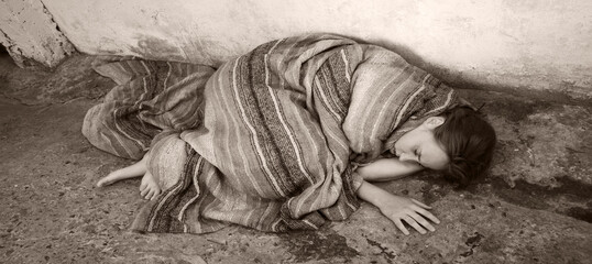 A girl in poor clothes lies on the ground