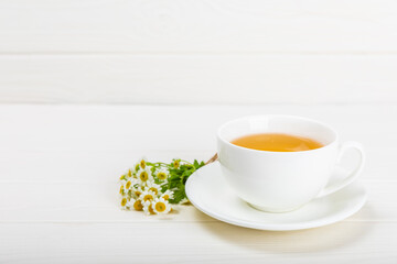 Chamomile herbal tea with flower buds, honey and lemon on a white wooden table and a bouquet of chamomile. Useful herbal, soothing drinks and natural healer concept. Immunity tea.Close up. Copy space.