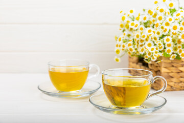 Chamomile herbal tea with flower buds, honey and lemon on a white wooden table and a bouquet of chamomile. Useful herbal, soothing drinks and natural healer concept. Immunity tea.Close up. Copy space.