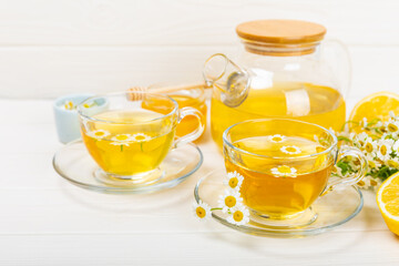 Chamomile herbal tea with flower buds, honey and lemon on a white wooden table and a bouquet of chamomile. Useful herbal, soothing drinks and natural healer concept. Immunity tea.Close up. Copy space.