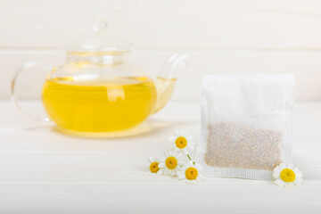 A bag of chamomile tea. Herbal chamomile tea in a bag on a white wooden background. Close-up. Copy...
