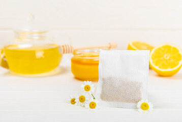Fototapeta na wymiar A bag of chamomile tea. Herbal chamomile tea in a bag on a white wooden background. Close-up. Copy space. healthy herbal drinks, immunity tea. Natural healer concept.Place for text.