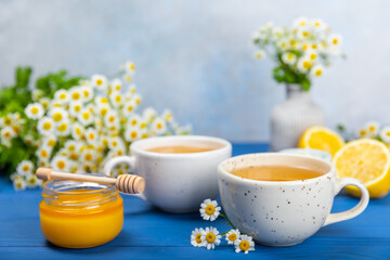 Chamomile herbal tea with flower buds on a blue wooden table and a bouquet of chamomile. Useful herbal, soothing drinks and natural healer concept. Immunity tea.Close up. Copy space.