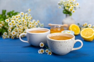 Chamomile herbal tea with flower buds on a blue wooden table and a bouquet of chamomile. Useful herbal, soothing drinks and natural healer concept. Immunity tea.Close up. Copy space.