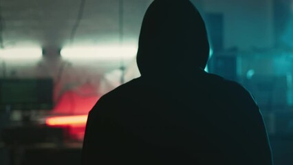 Mysterious cyber security hacker in hoodie in headquarter with computers - Powered by Adobe
