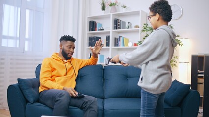 Young man refusing to play a game with his younger brother, bad relationship