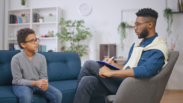African American psychologist talking with a boy, mental health assessment, support