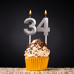 Birthday candle number 34 - Anniversary cupcake on black background