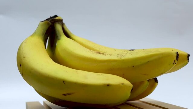 Fresh yellow bananas rotating on a wooden plate