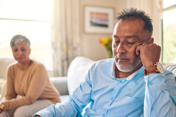 Couple arguing, stress and divorce with a senior man on a sofa in the living room of his home after a fight. Sad, anxiety or depression with an elderly male pensioner looking down after an problem
