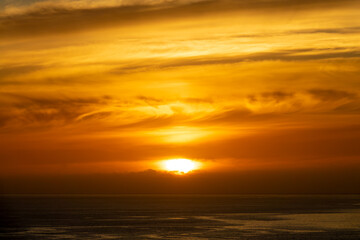 Fototapeta na wymiar Orange sky with clouds on the ocean at sunset in Madeira island, Portugal