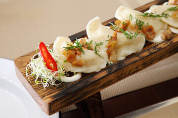 Dumplings with potatoes and salad. Dumplings with potatoes and greaves in sour cream on a wooden board and salad.
