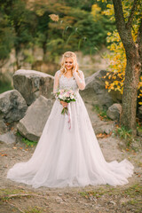 happy bride woman holding wedding creative bouquet white purple rose flowers berries eucalyptus plant bridal long white lush dress Girl blonde hair smiling face. autumn nature forest green trees.