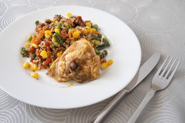 White plate with quinoa and vegetables and a piece of chicken
