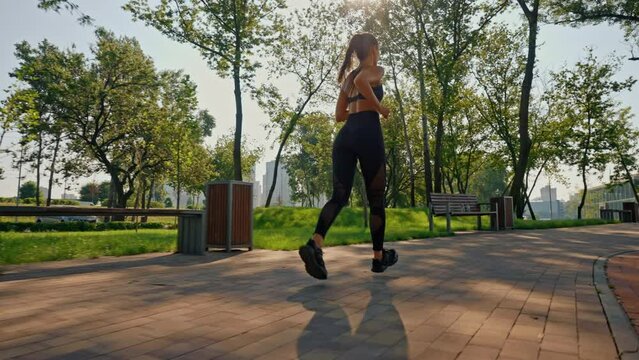 fitness woman jogging in park summer cardio exercise in sunny morning slow motion