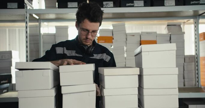 A red-haired man in a blue uniform and glasses checks the presence of all the boxes in the warehouse. Video filmed in high quality