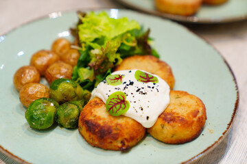 A plate with cutlets, new potatoes, Brussels sprouts and lettuce.