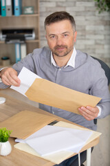 businessman reading a letter sitting in a desk at office