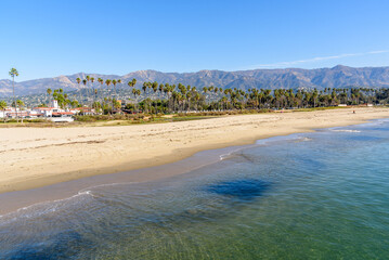 Fototapeta na wymiar View of the golden shore of Santa Barbara lined with palm trees with the mountains in background