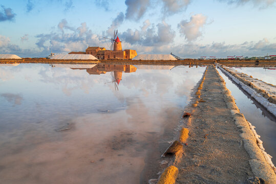Reflection of the windmill in the salt flats at dawn, Saline Ettore e Infersa, Marsala, province of Trapani, Sicily