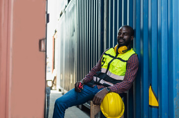 Black cargo worker sitting at container feeling tired from overwork in cargo seaport, Import Export and logistics Concept