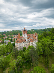 Fototapeta na wymiar Medieval Bran Castle, aerial drone perspective. Known as Dracula's Castle, it is visited annually by many foreign tourists. One of the best-known tourist attractions of Romania. Vertical photography.