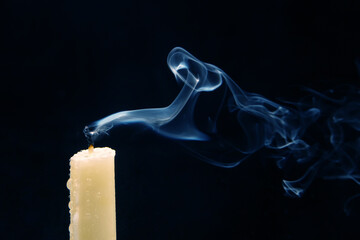 Smoke from an extinguished candle on a dark background. The concept of spirituality and the end of...