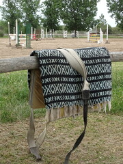 mandil y manta de una montura para caballo sobre un poste con el campo de fondo