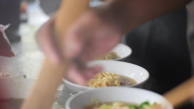 Preparing chicken noodles. View of a penjual mie ayam bakso or meatball chicken noodle seller who is making chicken noodles for the buyer. Selective focus. 